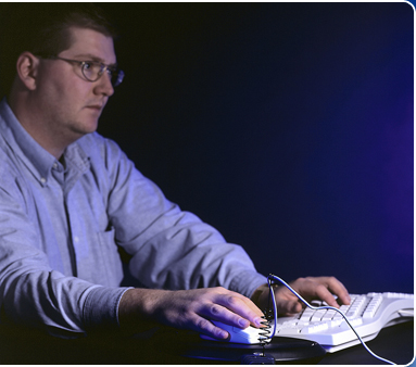 Image of a man with a keyboard and mouse on a dark background.